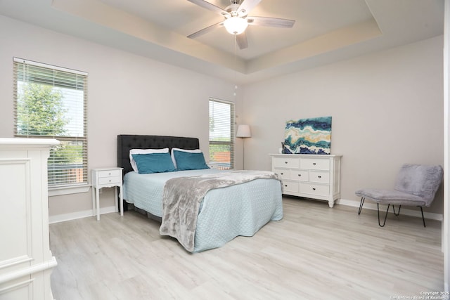 14946 Costa Leon, San Antonio, TX 78245 - bedroom featuring a tray ceiling, light wood-type flooring, multiple windows, and a ceiling fan