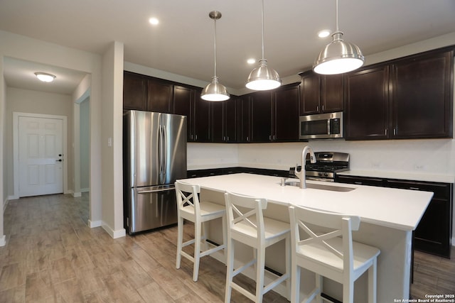 14946 Costa Leon, San Antonio, TX 78245 - kitchen with stainless steel appliances, light countertops, a kitchen breakfast bar, light wood-type flooring, and hanging light fixtures