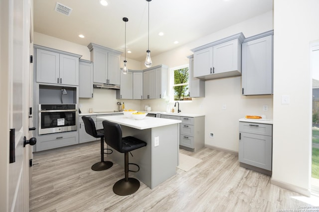 326 Cactus, San Antonio, TX 78203 - kitchen featuring oven, gray cabinetry, under cabinet range hood, a kitchen island, and recessed lighting