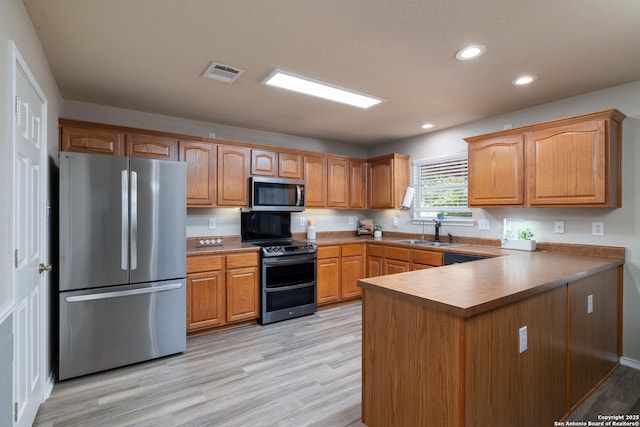 9915 Mustang Isle, San Antonio, TX 78254 - kitchen with appliances with stainless steel finishes, a peninsula, light wood finished floors, recessed lighting, and brown cabinetry