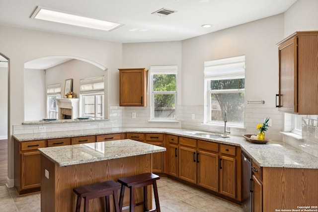 18310 Redwood Path, San Antonio, TX 78259 - kitchen with brown cabinets, a center island, decorative backsplash, light stone countertops, and light tile patterned floors