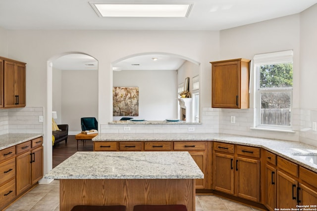 18310 Redwood Path, San Antonio, TX 78259 - kitchen featuring arched walkways, tasteful backsplash, and brown cabinets