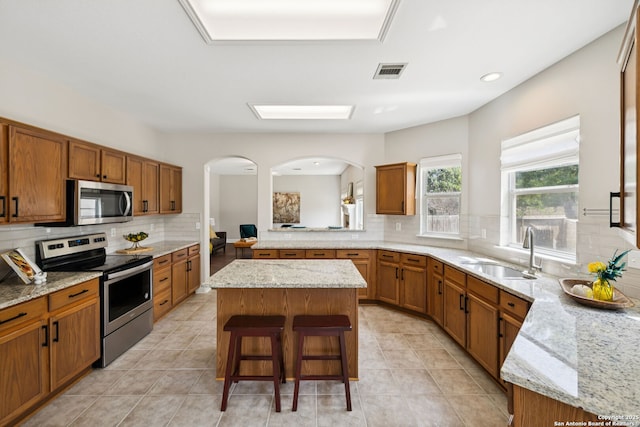 18310 Redwood Path, San Antonio, TX 78259 - kitchen featuring appliances with stainless steel finishes, tasteful backsplash, brown cabinetry, and a kitchen island