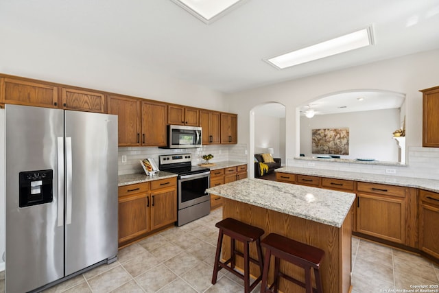 18310 Redwood Path, San Antonio, TX 78259 - kitchen with stainless steel appliances, decorative backsplash, arched walkways, and a center island