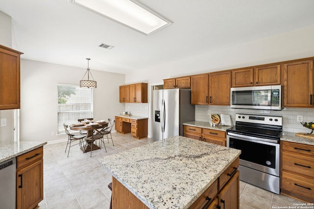 18310 Redwood Path, San Antonio, TX 78259 - kitchen featuring appliances with stainless steel finishes, backsplash, brown cabinetry, and decorative light fixtures