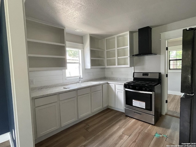603 Humboldt, San Antonio, TX 78211 - kitchen with stainless steel gas range, open shelves, wall chimney exhaust hood, a textured ceiling, and light wood-type flooring