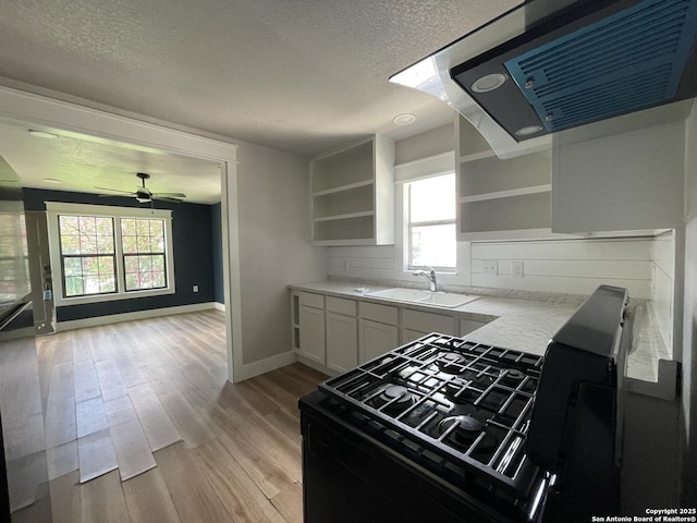 603 Humboldt, San Antonio, TX 78211 - kitchen featuring open shelves, a textured ceiling, light wood-style flooring, extractor fan, and white cabinets