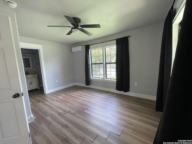 603 Humboldt, San Antonio, TX 78211 - unfurnished bedroom with a wall mounted AC, light wood finished floors, ceiling fan, and connected bathroom