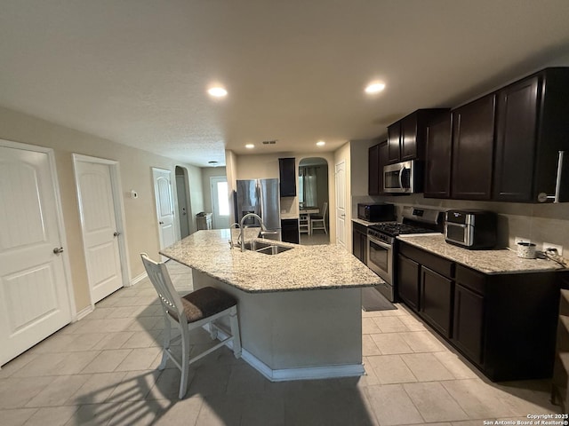 15530 Gray Catbird, San Antonio, TX 78253 - kitchen featuring appliances with stainless steel finishes, arched walkways, recessed lighting, an island with sink, and light stone countertops