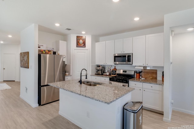 10626 Erinita, Converse, TX 78109 - kitchen with appliances with stainless steel finishes, light wood-style floors, white cabinets, a kitchen island with sink, and recessed lighting