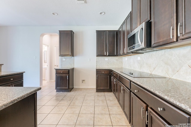 20131 Silver, San Antonio, TX 78259 - kitchen with stainless steel microwave, arched walkways, dark brown cabinetry, decorative backsplash, and recessed lighting
