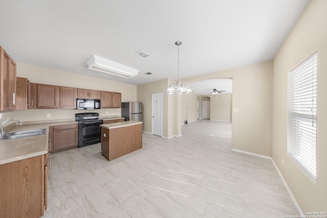 5715 Sendero Spg, San Antonio, TX 78251 - kitchen featuring black appliances, a kitchen island, light countertops, open floor plan, and light marble finish flooring