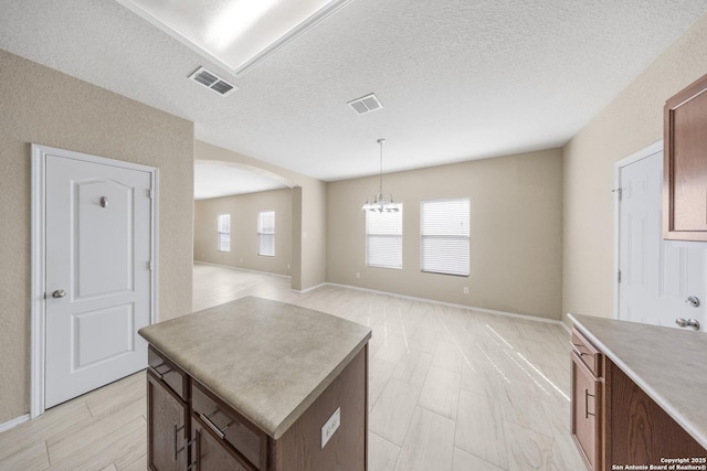5715 Sendero Spg, San Antonio, TX 78251 - kitchen featuring arched walkways, plenty of natural light, a center island, a chandelier, and a textured ceiling