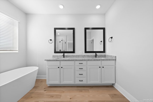 159 Azalea Aly, Castroville, TX 78009 - full bathroom featuring double vanity, a freestanding tub, wood finished floors, an enclosed shower, and recessed lighting