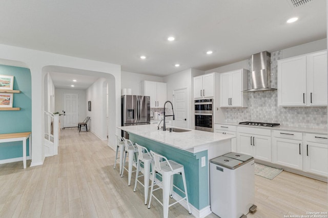 29949 Premiere, Bulverde, TX 78163 - kitchen with wall chimney exhaust hood, appliances with stainless steel finishes, arched walkways, light wood finished floors, and backsplash