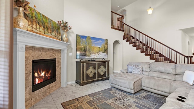 12618 Ozona Rnch, San Antonio, TX 78245 - living room with arched walkways, a high ceiling, marble look tiles, a tile fireplace, and stairs