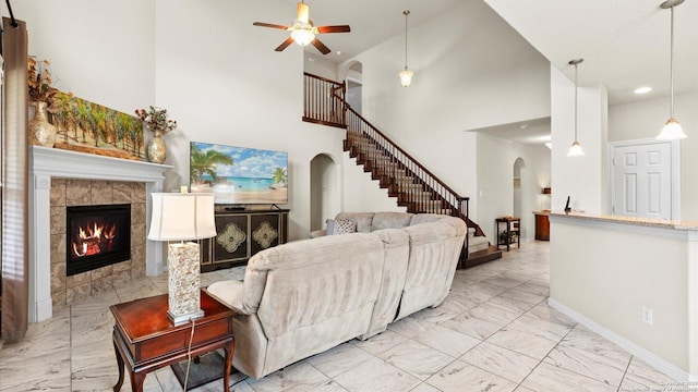 12618 Ozona Rnch, San Antonio, TX 78245 - living room with arched walkways, light marble finish floors, a high ceiling, a tiled fireplace, and stairs