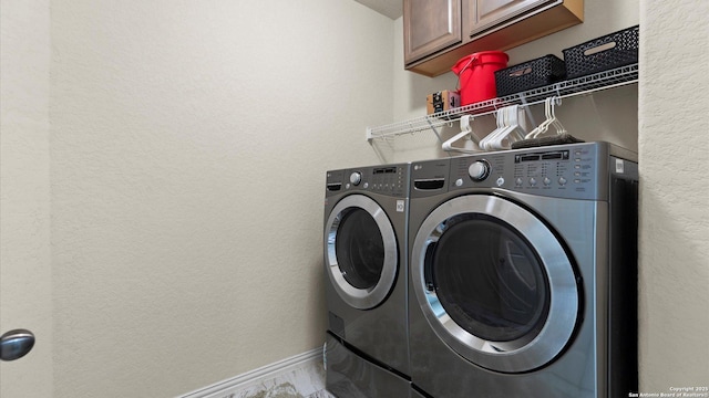 12618 Ozona Rnch, San Antonio, TX 78245 - laundry area with cabinet space, washing machine and clothes dryer, a textured wall, and marble finish floors