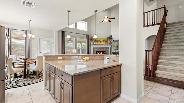 12618 Ozona Rnch, San Antonio, TX 78245 - kitchen with light marble finish floors, a lit fireplace, light stone counters, a ceiling fan, and a towering ceiling