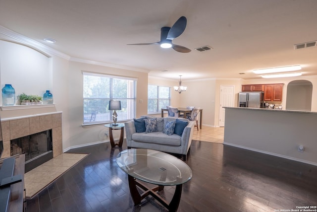 9534 Anderson Way, Converse, TX 78109 - living room with a tile fireplace, a ceiling fan, ornamental molding, wood-type flooring, and a chandelier