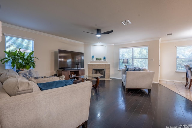 9534 Anderson Way, Converse, TX 78109 - living room featuring a tile fireplace, crown molding, a ceiling fan, and plenty of natural light