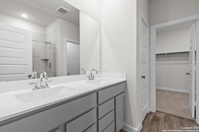 9962 Forestier Grn, San Antonio, TX 78214 - full bathroom with double vanity, a walk in closet, a tile shower, and wood finished floors