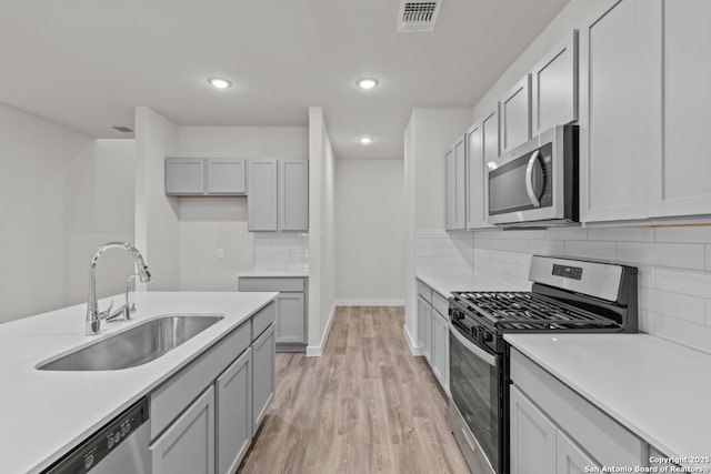9962 Forestier Grn, San Antonio, TX 78214 - kitchen featuring appliances with stainless steel finishes, light wood-style flooring, light countertops, decorative backsplash, and recessed lighting