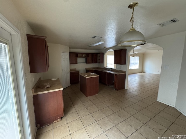 6547 Estes Flts, San Antonio, TX 78242 - kitchen featuring arched walkways, a kitchen island, light tile patterned flooring, a heating unit, and a textured ceiling