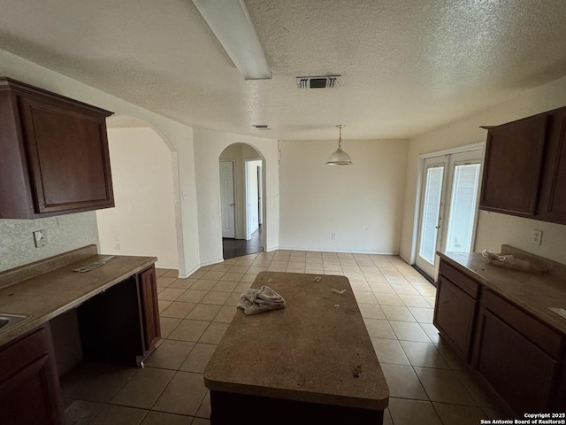 6547 Estes Flts, San Antonio, TX 78242 - kitchen featuring tile patterned floors, arched walkways, a textured ceiling, pendant lighting, and a center island