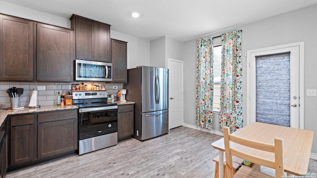 6314 Hibiscus Fls, San Antonio, TX 78218 - kitchen featuring stainless steel appliances, dark brown cabinetry, light wood finished floors, decorative backsplash, and light stone counters