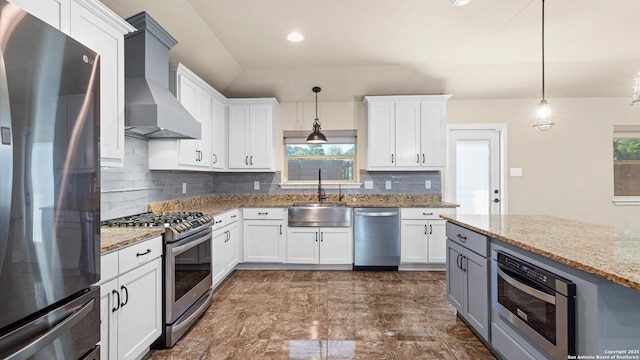 1069 Ivy Ln, Terrell Hills, TX 78209 - kitchen featuring appliances with stainless steel finishes, wall chimney exhaust hood, tasteful backsplash, white cabinetry, and recessed lighting