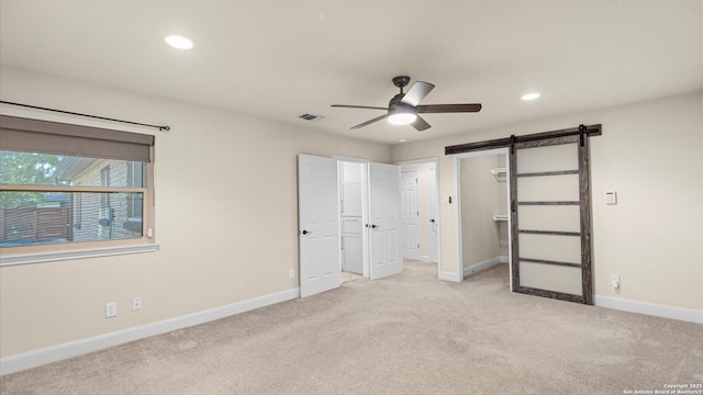 1069 Ivy Ln, Terrell Hills, TX 78209 - unfurnished bedroom featuring a barn door, light colored carpet, recessed lighting, a spacious closet, and a ceiling fan