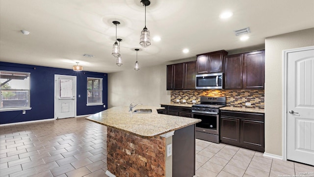 702 Pelican Pt, San Antonio, TX 78221 - kitchen featuring stainless steel appliances, backsplash, light tile patterned floors, dark brown cabinetry, and an island with sink