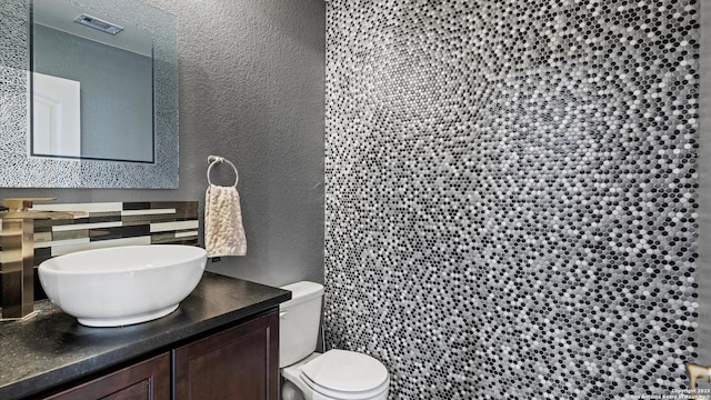 702 Pelican Pt, San Antonio, TX 78221 - bathroom with a textured wall, vanity, and decorative backsplash