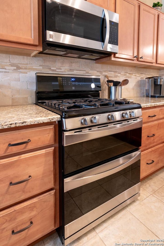 12610 Lotus Rdg, San Antonio, TX 78253 - kitchen featuring appliances with stainless steel finishes, backsplash, light stone counters, and light tile patterned floors