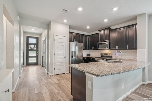 4931 Ranahan Pass, Saint Hedwig, TX 78152 - kitchen with stainless steel appliances, light stone countertops, light wood-style floors, a peninsula, and recessed lighting