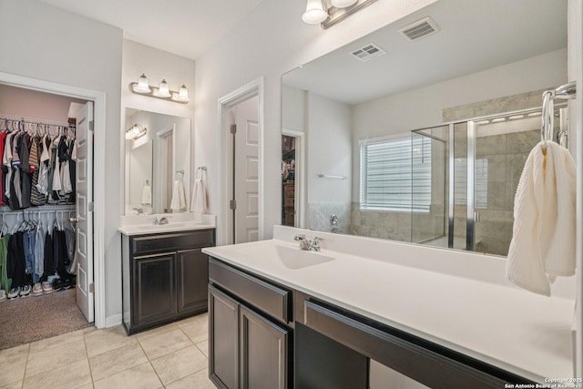 4931 Ranahan Pass, Saint Hedwig, TX 78152 - bathroom featuring a walk in closet, two vanities, a stall shower, and tile patterned floors