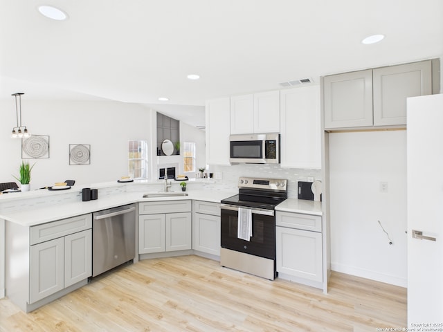 7007 Elk Trl, San Antonio, TX 78244 - kitchen featuring appliances with stainless steel finishes, light wood-style flooring, light countertops, gray cabinetry, and a peninsula
