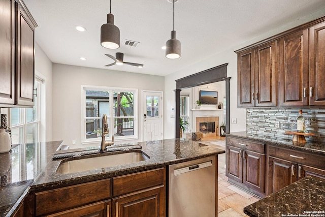 1159 Bluff Frst, San Antonio, TX 78248 - kitchen with stainless steel dishwasher, a ceiling fan, a glass covered fireplace, dark stone counters, and tasteful backsplash
