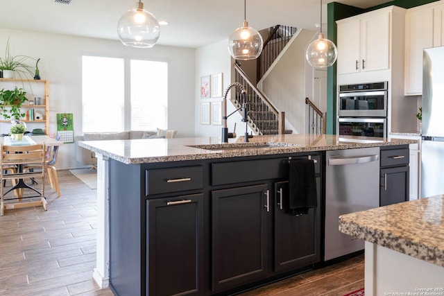 5944 Sterling Vw, Schertz, TX 78108 - kitchen with stainless steel appliances, wood finished floors, white cabinetry, open floor plan, and decorative light fixtures