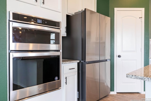 5944 Sterling Vw, Schertz, TX 78108 - kitchen featuring appliances with stainless steel finishes, white cabinetry, light wood-style floors, and light stone counters