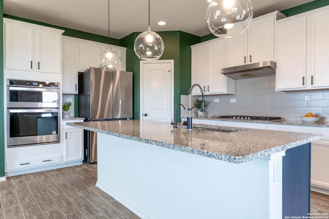 5944 Sterling Vw, Schertz, TX 78108 - kitchen featuring under cabinet range hood, stainless steel appliances, tasteful backsplash, a kitchen island with sink, and light stone countertops