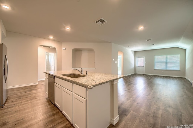 3008 Pemberton Post, San Antonio, TX 78245 - kitchen featuring arched walkways, an island with sink, stainless steel appliances, wood finished floors, and light stone counters