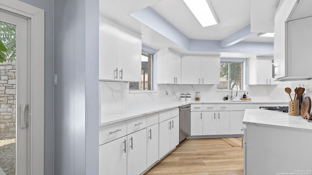 1318 Mount Vieja, San Antonio, TX 78213 - kitchen with stainless steel dishwasher, white cabinets, backsplash, light wood-type flooring, and light stone counters