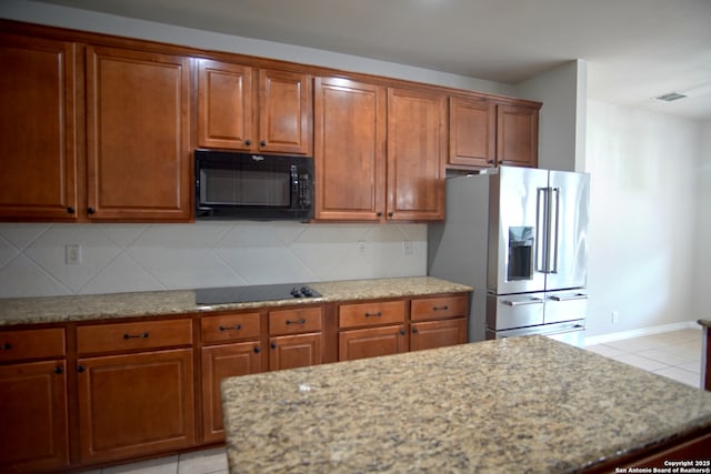24123 Horse Pr, San Antonio, TX 78261 - kitchen featuring black appliances, brown cabinetry, tasteful backsplash, and light stone countertops