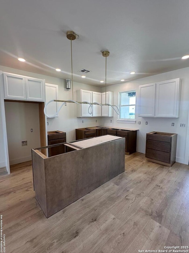 129 Merion Ln, Vernia, TX 78121 - kitchen with white cabinetry, recessed lighting, light wood-type flooring, and decorative light fixtures