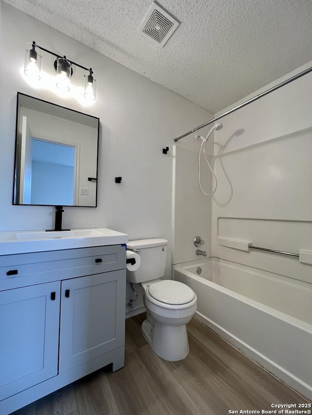 7947 Ruby Mdws, San Antonio, TX 78251 - bathroom with a textured ceiling, wood finished floors, vanity, and tub / shower combination