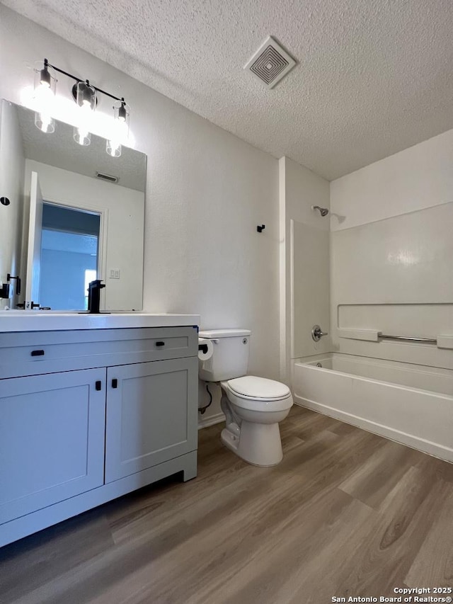 7947 Ruby Mdws, San Antonio, TX 78251 - bathroom with vanity, a textured ceiling, wood finished floors, and shower / bath combination