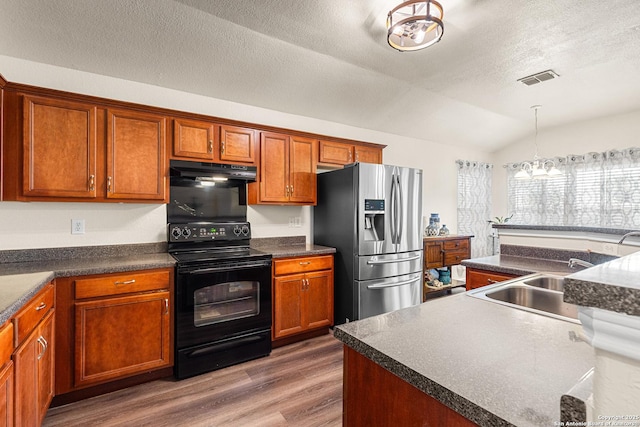 9235 Everton, San Antonio, TX 78245 - kitchen featuring black range with electric stovetop, stainless steel fridge with ice dispenser, under cabinet range hood, vaulted ceiling, and wood finished floors