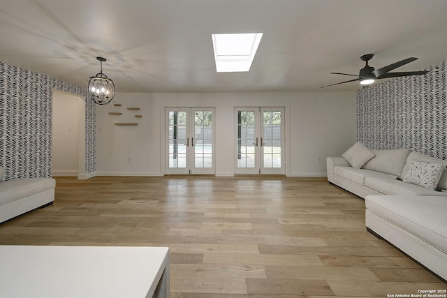 5738 Brenda Ln, San Antonio, TX 78240 - unfurnished living room featuring a skylight, ceiling fan, light wood finished floors, and a chandelier